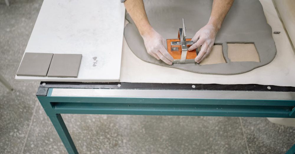 Tile Cutters - A person shaping clay using a cutter to craft tiles on a worktable.