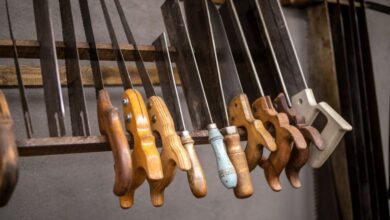 Hand Saws - Assorted vintage hand saws with wooden handles neatly displayed in a workshop setting.