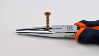 Pliers - High-quality image of long nose pliers gripping a metal screw on a neutral background.
