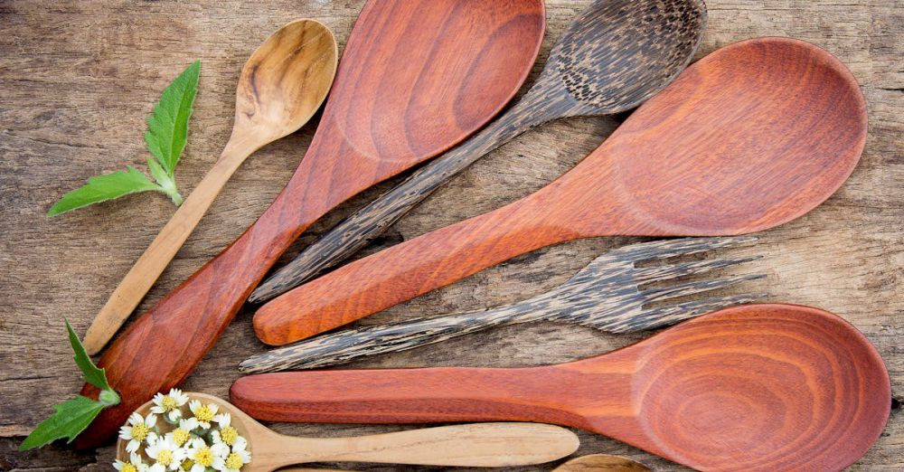 Kitchenware - Top view of rustic wooden kitchen utensils and small flowers on a textured table.