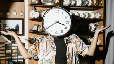 Antique Clocks - A creative photo of a person with a clock obscuring their face, surrounded by vintage clocks on wooden shelves.