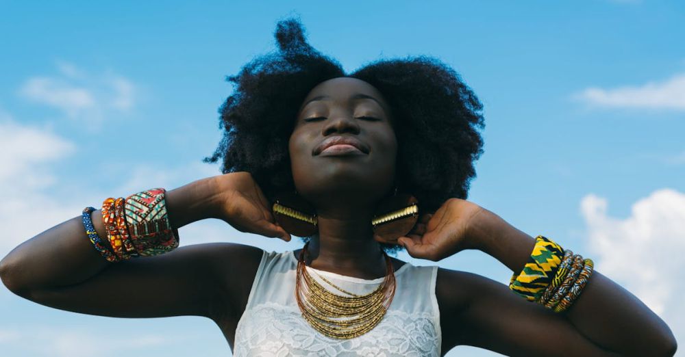 Accessories - Portrait of a joyful African woman with afro hair, wearing colorful bracelets and gold earrings, enjoying the sunny day.