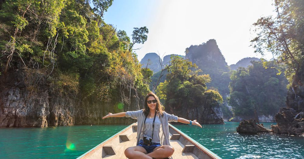 Tours - Asian woman relishing a serene boat journey through the lush karst landscape of Thailand's Khlong Sok.