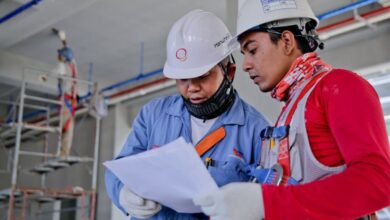 Safety - Two engineers in safety helmets reviewing construction plans at a worksite.