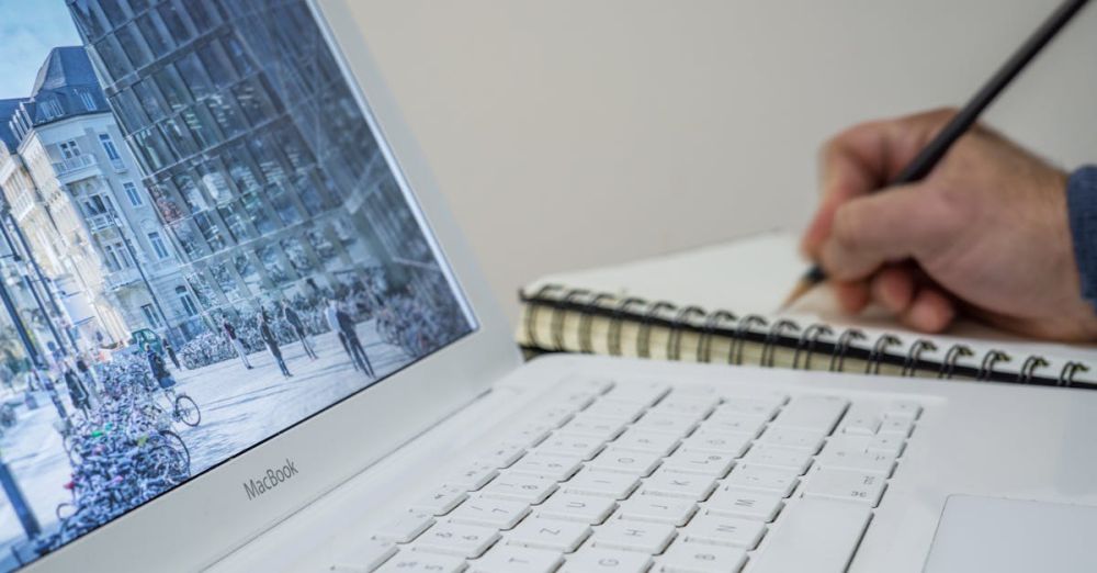 Preparation - A person taking notes in a notebook beside an open laptop displaying an urban scene.