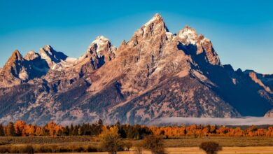 Destinations - Breathtaking autumn landscape of Grand Teton with snow-capped peaks and colorful trees.