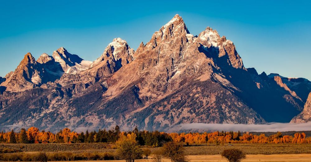 Destinations - Breathtaking autumn landscape of Grand Teton with snow-capped peaks and colorful trees.