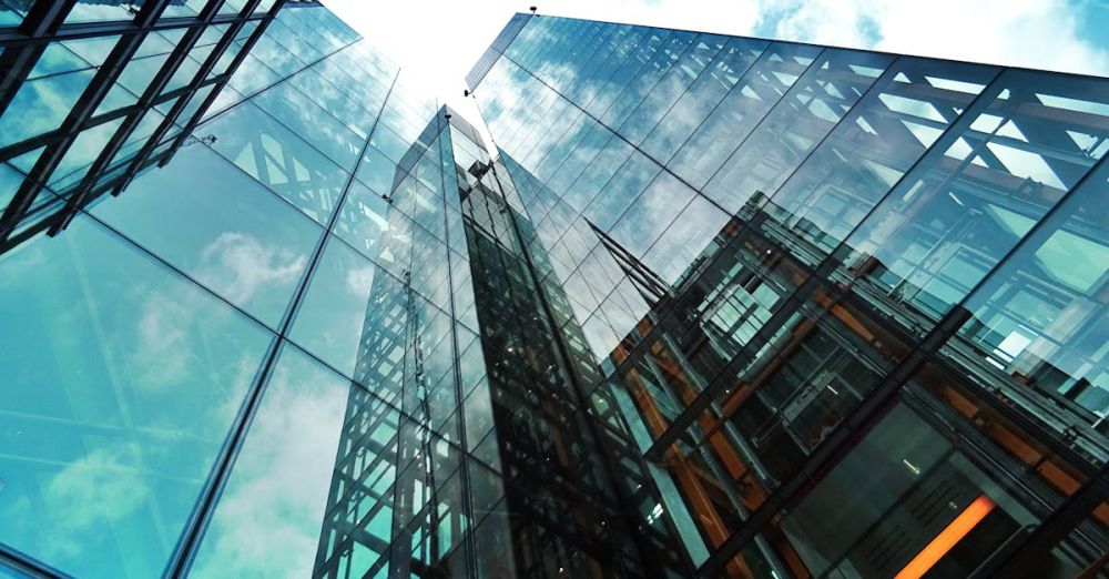 Companies - A striking view of a modern glass skyscraper reflecting the sky and clouds.