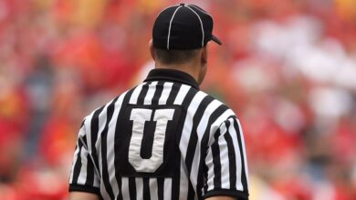 Rules - A football umpire in uniform overseeing the game in a crowded stadium.