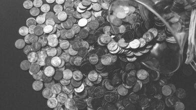 Budget - Monochrome image of coins spilling from a glass jar, symbolizing wealth and savings.