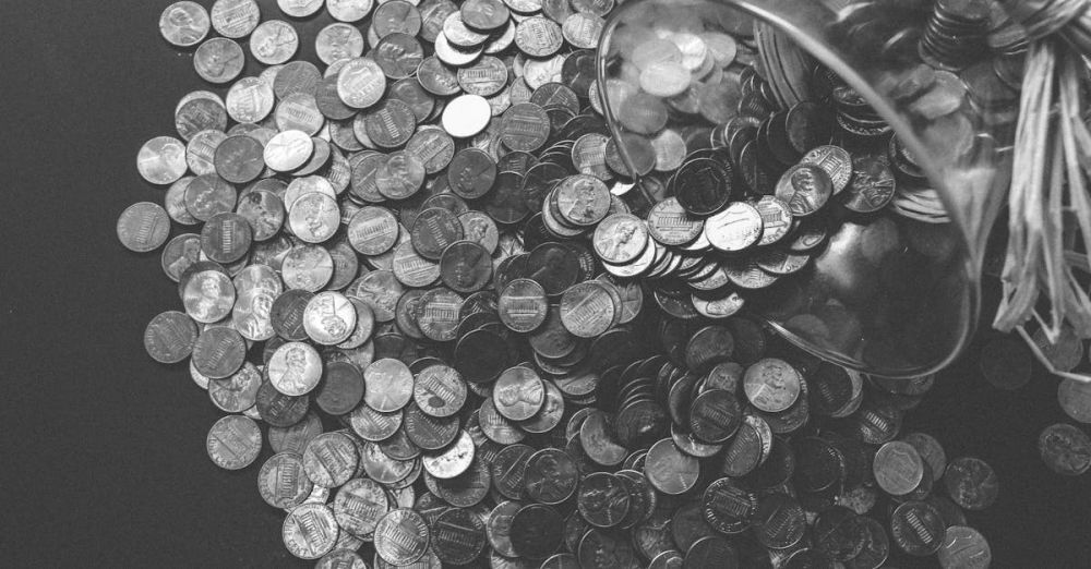 Budget - Monochrome image of coins spilling from a glass jar, symbolizing wealth and savings.