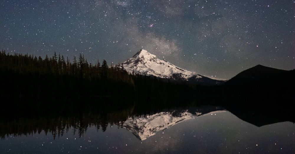 Nighttime - Snow-capped Mount Hood reflected in a serene lake under a starry sky, Oregon.