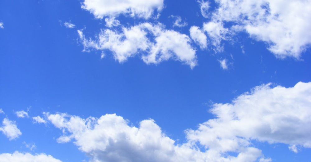 Day - Vibrant cumulus clouds adorn a clear blue sky, creating a serene and dreamy cloudscape.