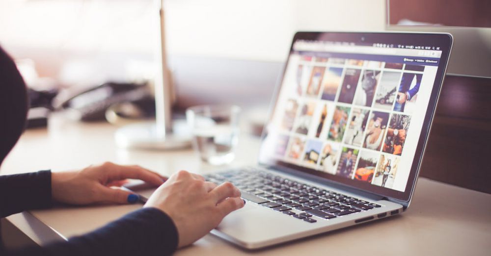 Photos - Close-up of hands typing on a laptop with an image gallery open on the screen.