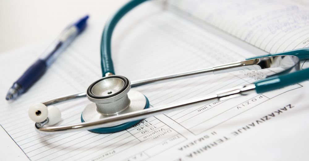 Health - A stethoscope and pen resting on a medical report in a healthcare setting.