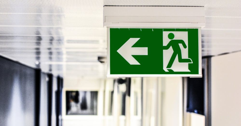 Safety - Green emergency exit sign with directional arrow in a hallway.