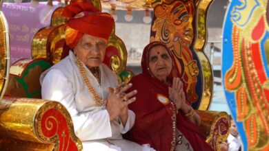 Cultural Significance - Elderly couple in colorful Indian attire sitting on a decorated ceremonial seat at a festival.