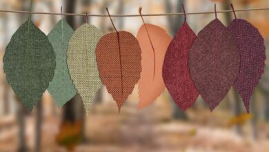 Seasons - Fabric leaves hang on a rope, showcasing autumn colors in a forest backdrop.