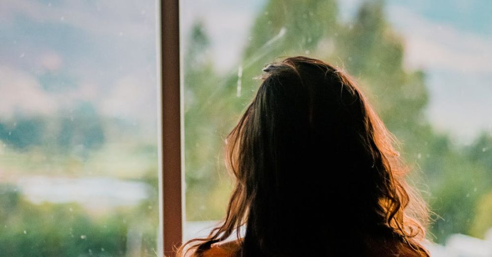 Miss - Silhouette of a woman looking out a window at a scenic mountain view in Cajamarca, Peru.