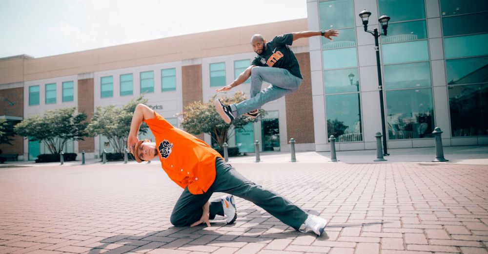 Beginners - Two men performing breakdancing moves in an urban outdoor setting.