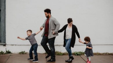 Families - A joyful family walking together outdoors, holding hands in a playful and happy moment.