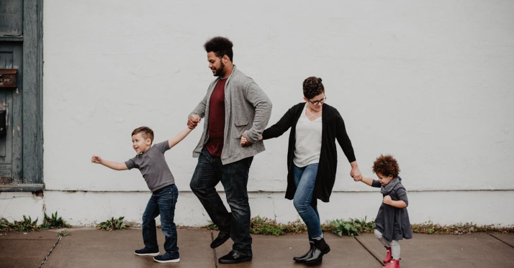 Families - A joyful family walking together outdoors, holding hands in a playful and happy moment.