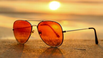 Summer - Close-up of sunglasses on a beach during a vibrant sunset, capturing the essence of summer.