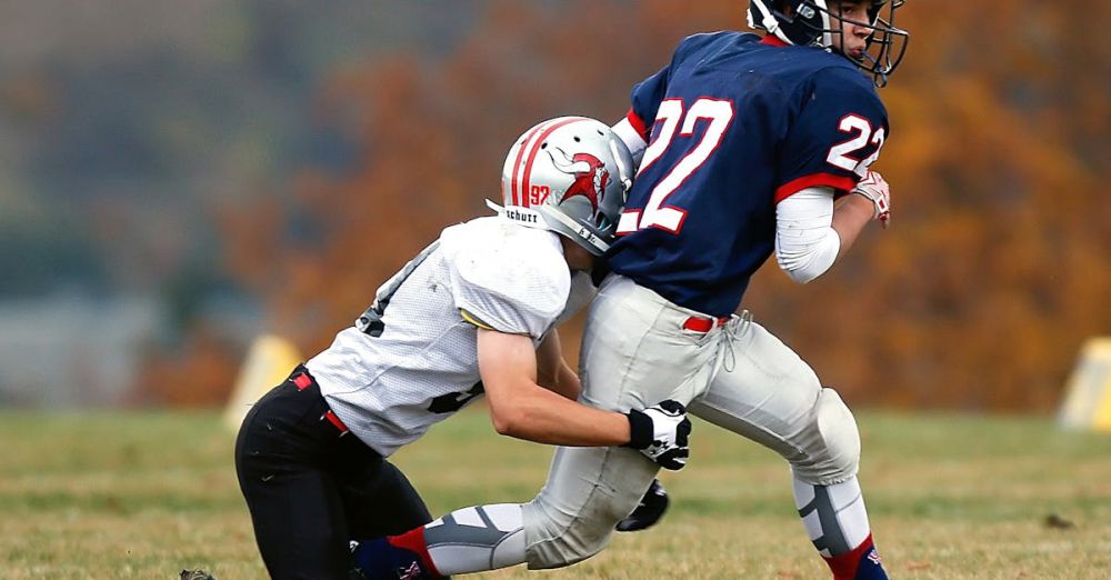 Challenging Runs - Two athletes in action during an intense outdoor American football game on a grassy field.