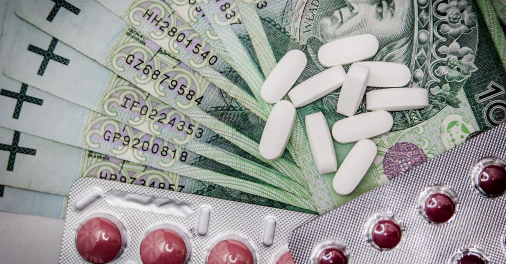 Cost - Polish 100 złoty notes with pills and blister packs, illustrating medical costs.