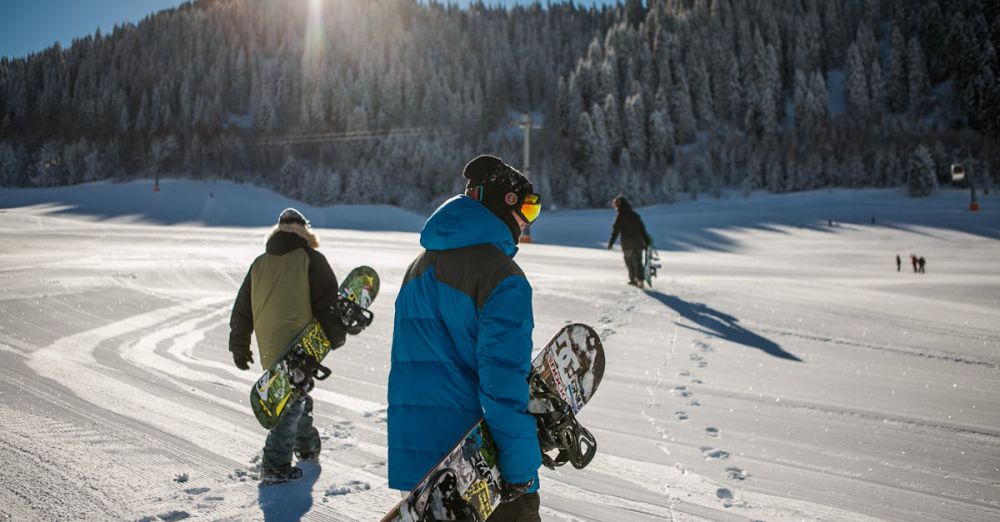 Snowboarders - Group of snowboarders walking up a snowy ski slope during a sunny winter day in the mountains.