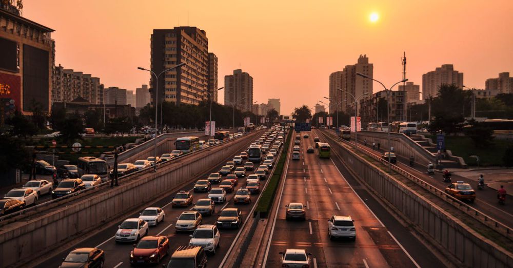 Transportation - A bustling urban highway with heavy traffic under a vibrant sunset sky against a cityscape backdrop.