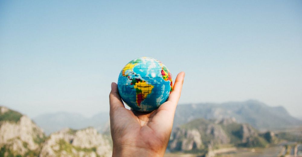 Trip Planning - Hand holding a globe against a mountain background symbolizing travel and exploration.