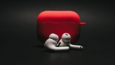 Earbuds - Sleek white earbuds with modern red case on a dark surface, highlighting stylish audio technology.