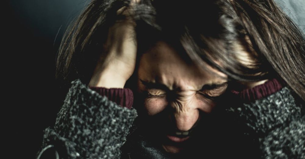 Difficulty - Close-up of a woman in distress with eyes closed and hands in hair, expressing anxiety.