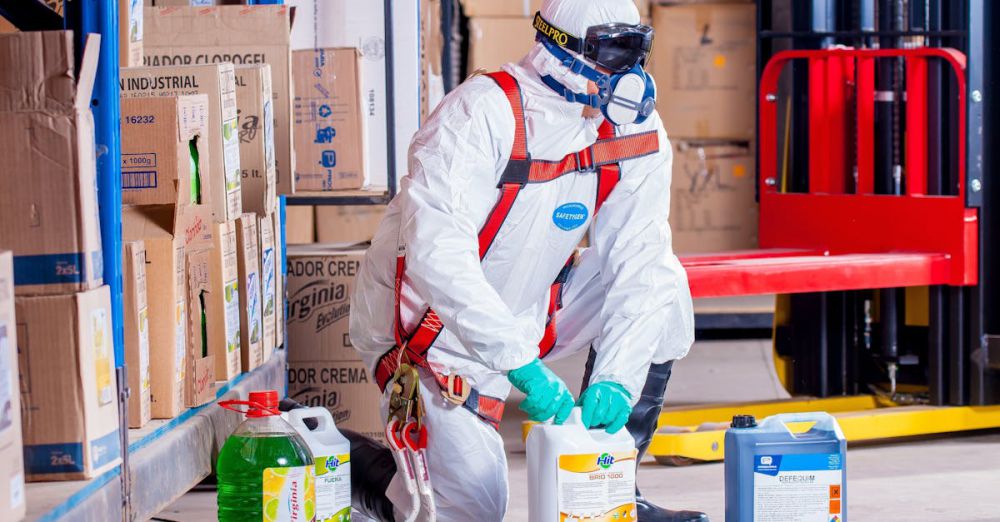 Safety - Industrial worker in protective gear handling chemicals in a warehouse environment.