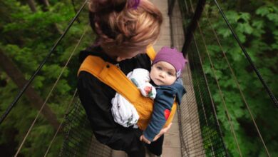 Family Trails - A woman carries her baby over a forest suspension bridge, highlighting maternal care.