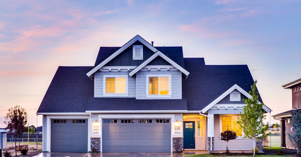 Home - Beautiful two-story house with illuminated windows and garage at dusk.