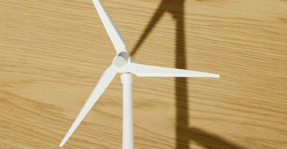 Energy - Close-up of a hand holding a small wind turbine model casting a shadow on a wooden surface.