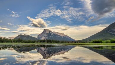 Rockies - Serene landscape of Banff National Park with mountains and lake reflections at sunrise.