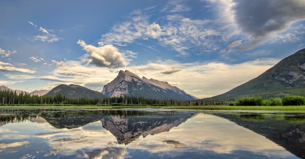 Rockies - Serene landscape of Banff National Park with mountains and lake reflections at sunrise.