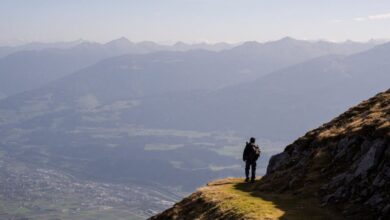 Solo Hiking - A lone hiker stands on a mountain path overlooking the vast Austrian Alps near Innsbruck.