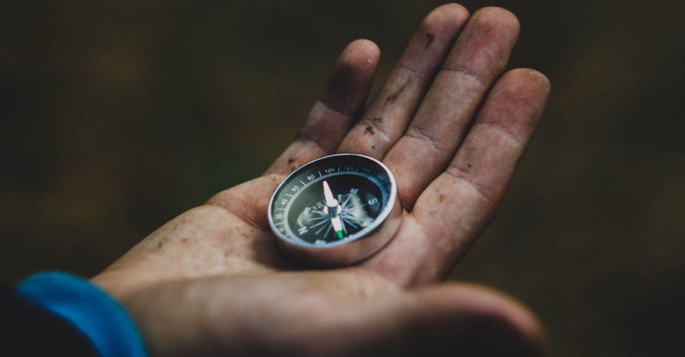 Lost - A close-up of a compass held in a dirty hand, symbolizing adventure and navigation.