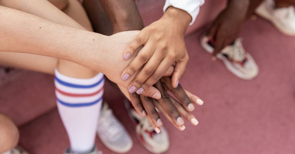 Training - A group of friends stack their hands in unity on a sports court, symbolizing teamwork.