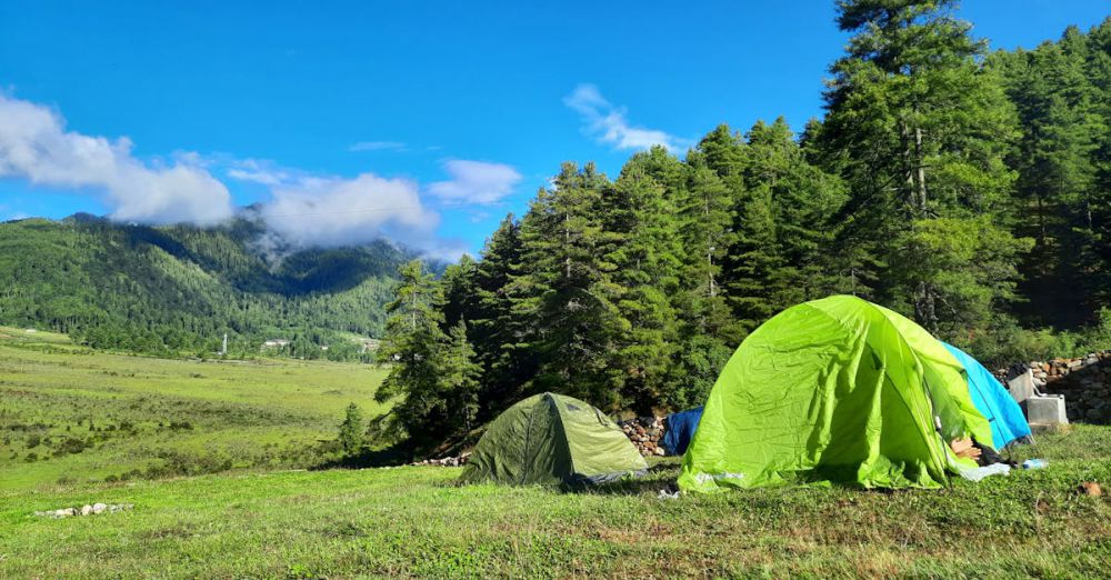 Camping Spots - Explore serene camping with green tents amidst Bhutan's lush landscapes under a vibrant blue sky.