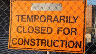 Permit - Orange sign behind fence reading 'Temporarily Closed for Construction' at site.