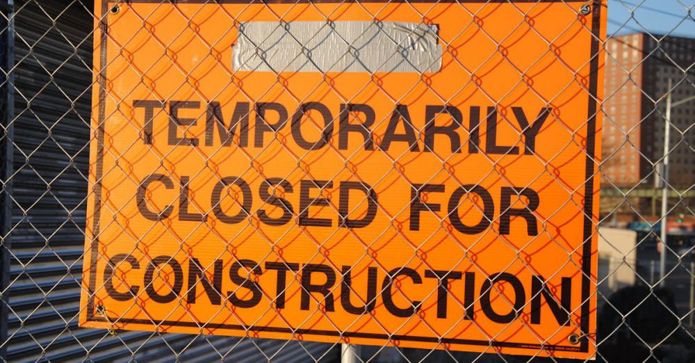 Permit - Orange sign behind fence reading 'Temporarily Closed for Construction' at site.