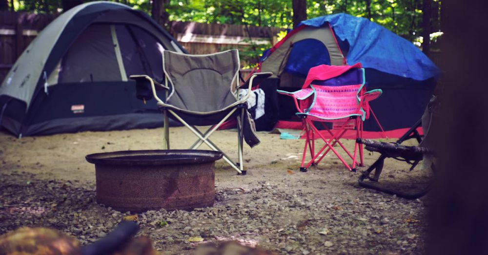 Campsite - A serene campsite in the woods with colorful tents, camping chairs, and a fire pit, perfect for a leisure getaway.