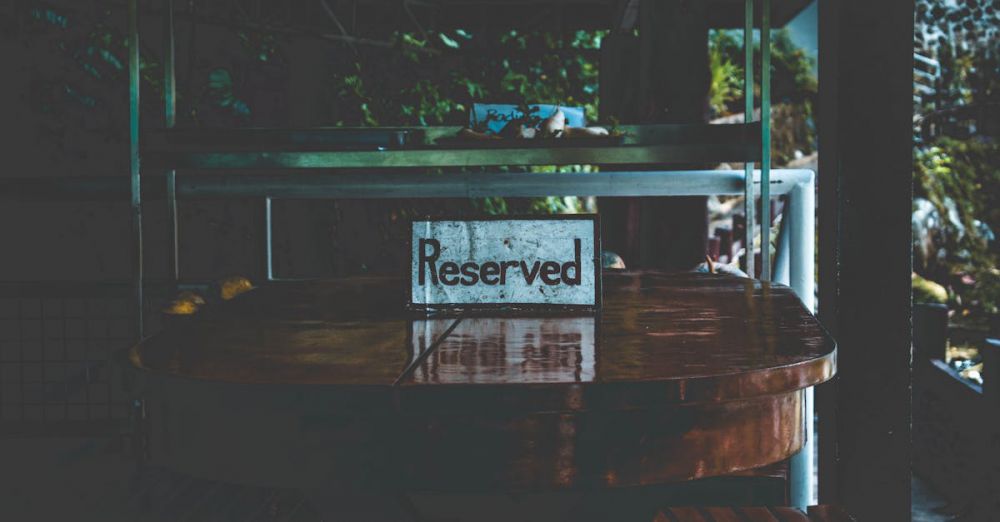 Reservation - A dimly lit table with a reserved sign, set in an outdoor environment creating a moody atmosphere.