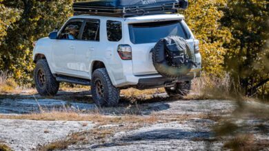 Scenic Camping - White SUV parked on a rocky terrain in a forested area, showcasing outdoor adventure.