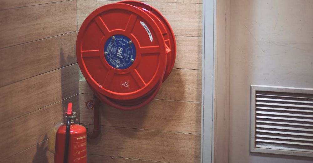 Safety - Red fire hose reel and extinguisher inside a building corner.